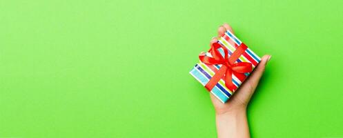 Top view of female hands holding christmas or other holiday handmade present box package in the palms, flat lay table background with copy space photo