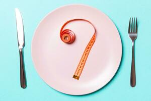 Fork and plate with measuring tape on color background. Diet concept photo