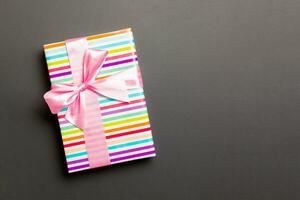 Gift box with pink bow for Christmas or New Year day on black background, top view with copy space photo