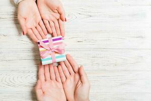 Top view of giving a present to a lovely person on wooden background. Couple congratulate each other. Festive concept. Copy space photo