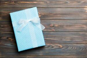 Beautiful gift box with a colored bow on the dark wooden table. Top view banner with copy space for you design photo