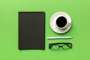 Modern office desk table with notebook and other supplies with cup of coffee. Blank notebook page for you design. Top view, flat lay photo