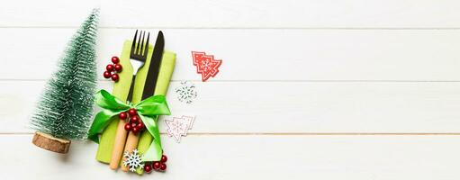 Top view Banner of fork and knife tied up with ribbon on napkin on wooden background. Christmas decorations and New Year tree. Happy holiday concept with empty space for your design photo