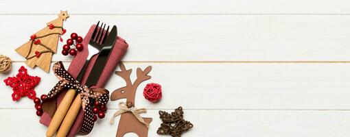 Top view of new year utensils on napkin with holiday decorations and reindeer on wooden background. Banner Christmas dinner concept with copy space photo