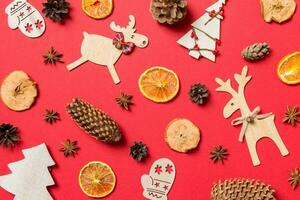 Top view of red background decorated with festive toys and Christmas symbols reindeers and New Year trees. Holiday concept photo