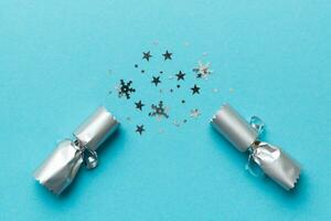 Christmas crackers with shiny confetti on color background, top view, copy space photo