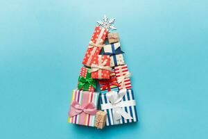 Christmas tree made of beautifuly wrapped presents on colored background, view from above. New Year gift box minimal concept with copy space photo