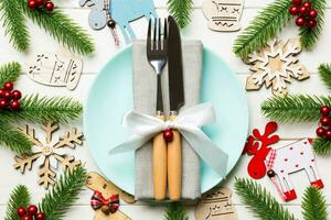 Top view of New Year dinner on festive wooden background. Composition of plate, fork, knife, fir tree and decorations. Merry Christmas concept photo