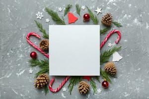 Flat lay Christmas composition. square Paper blank, pine tree branches, christmas decorations on Colored background. Top view, copy space for text photo