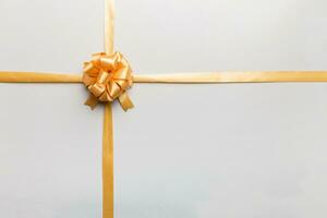 Top view of gold ribbon rolled and yellowbow isolated on colored background. Flat lay with copy space photo