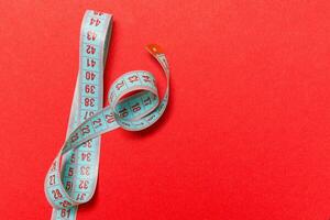 Top view of measuring tape on red background. Tailor and slim waist concept with emty space for your idea photo