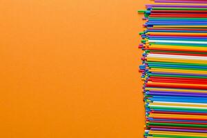 Heap of colorful plastic drinking straws on Colored background, flat lay. Copy Space for text photo