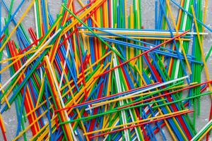 many multi-colored plastic tubes for cocktail on Colored background, top view photo