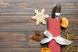 Top view of utensils on festive napkin on wooden background. Christmas decorations with dried fruits and cinnamon. New year dinner concept with copy space photo