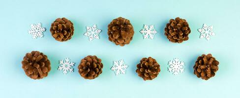 Top view of New Year ornament made of white snowflakes and pine cones on colorful background. Banner winter holiday concept with empty space for your design photo