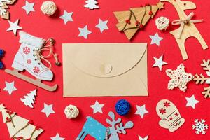 Top view of craft envelope, holiday toys and decorations on red Christmas background. New Year time concept photo