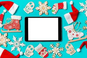 Top view of digital tablet with Christmas decorations and Santa hats on blue background. Happy holiday concept photo