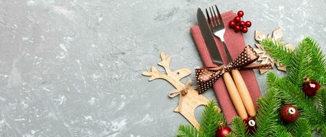 Top view of flatware tied up with ribbon on napkin on cement background. Banner Christmas decorations and reindeer with empty space for your design. New Year holiday concept photo
