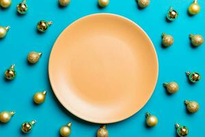 Top view of festive plate with golden baubles on colorful background. Christmas decorations and toys. New Year advent concept photo