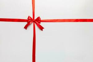 Top view of Red ribbon rolled and red bow isolated on colored background. Flat lay with copy space photo