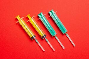 Top view of medical syringes with needles at red background with copy space. Injection treatment concept photo