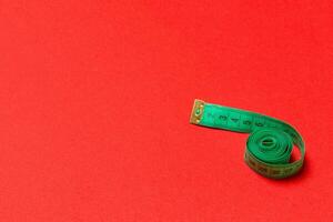 Top view of curled measuring tape as a sewing accessory on red background. Tailor concept with copy space photo