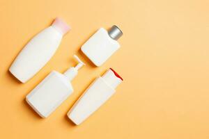 Set of White Cosmetic containers isolated on colored background, top view with copy space. Group of plastic bodycare bottle containers with empty space for you design photo