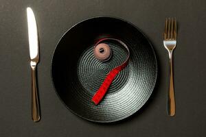 Fork and plate with measuring tape on color background. Diet concept photo