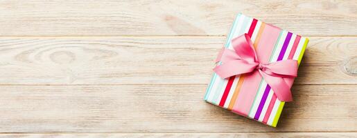 paper gift box with colored ribbon on orange wood background. top view with copy space Christmas holiday concept photo