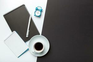 Modern office desk table with notebook and other supplies with cup of coffee. Blank notebook page for you design. Top view, flat lay photo