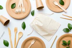 set of empty reusable disposable eco-friendly plates, cups, utensils on light white colored table background. top view. Biodegradable craft dishes. Recycling concept. Close-up photo