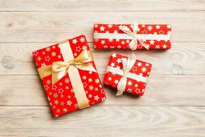 paper gift box with colored ribbon on orange wood background. top view with copy space Christmas holiday concept photo