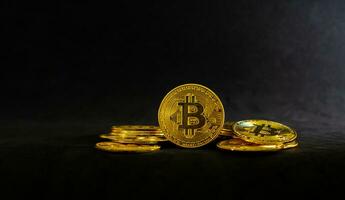 Golden bitcoin in the middle of pile, Bitcoin on black table with black background. photo