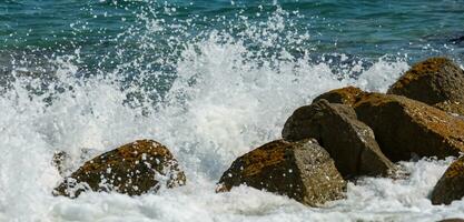 mar agua golpes rocas en el playa por el mar con fuerte olas foto