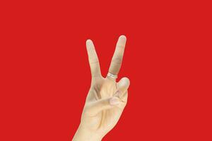 Female hand showing victory sign isolated on red background with copy space for text. photo