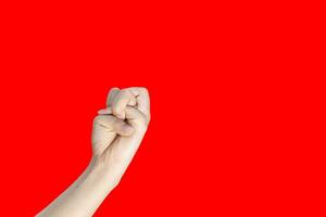 Female hand with clenched fist isolated on red background with copy space. photo