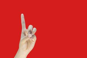 Female hand index finger pointing up on red background with copy space, business concept photo