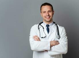 ai atención.sanitaria.generativa, médico personal concepto. retrato de sonriente masculino médico posando con doblada brazos en gris estudio fondo, gratis espacio. profesional general practicante.ai-generado. foto