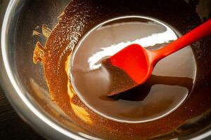 Woman cooking tasty melted chocolate on table in kitchen. photo