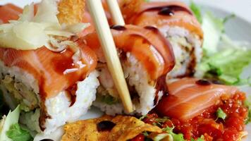 View of fusion salmon sushi rolls with sauce on white plate. Healthy and fusion japanese food style concept video