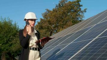 donne d'affari Lavorando su controllo attrezzatura a solare energia pianta con tavoletta lista di controllo, smartphone. femmina Lavorando su un innovativo Di Più efficiente solare pannello batteria concetto. video