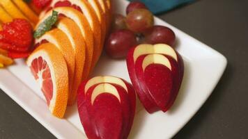Festive fruits plate with cut fruit pieces on skewers in white plate. Dessert for birthday party, sweet appetizer video