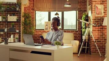 Woman scrolling on social media using smartphone, taking small break from freelance writing job at home. Teleworker searching information on webpages, working remotely during sunset hour. video