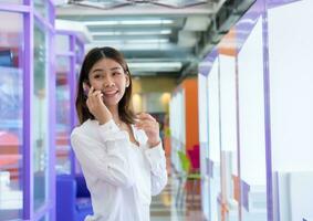 Beautiful young asian business woman is standing and using a phone to do business with a happy expression, Digital marketing. photo