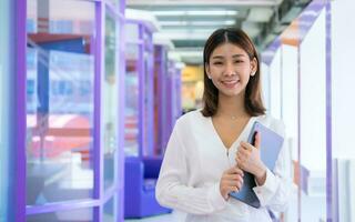 Beautiful asian business woman is standing facing the camera while holding a tablet with a happy expression and a smile, Digital marketing. photo