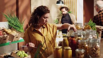 Vegan woman in specialty zero waste supermarket smelling bulk items before adding them to shopping basket. Client in local neighborhood shop testing to see if food is toxins free before buying it video