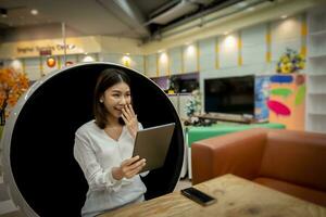 Beautiful office lady was surprised about her sales this month while sitting on a modern round chair in the living room. photo