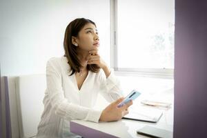 Beautiful asian businesswoman is coming up with a project to present to her boss on her desk at her office. photo