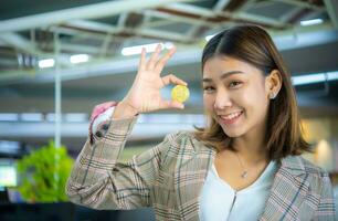 Happy beautiful asian business woman holding bitcoin while looki photo