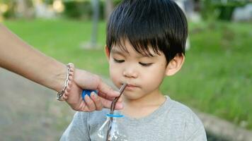 asiatisch Junge Trinken Wasser von ein Flasche gehaltenen durch seine Mutter video